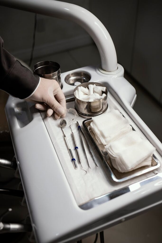 Close-up of dental tools on a tray with a gloved hand in a dental office setting.